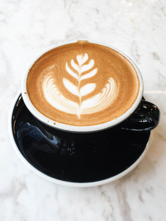 close up of a hot coffee cup with latte art on white marble tableの写真素材