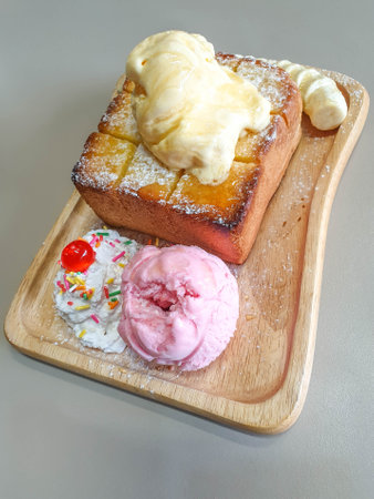honey toast with strawberry ice-cream, bananas,whipped cream, jelly and sprinkles on topの写真素材