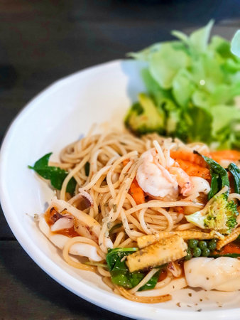 Spicy spaghetti with mixed seafood and herb on white plateの写真素材