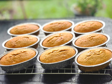 banana sponge cake in alumenium foil container on baking cooling rack