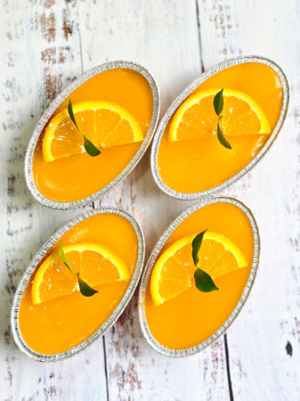 orange cake with sliced fresh orange and green tree leaf in alumenum foil containerの写真素材