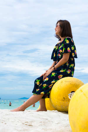 Girl sitting on buoy near seaの写真素材