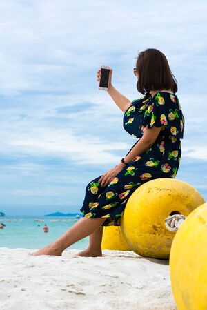 Girl sitting on buoy near sea take a photo with herselfの写真素材