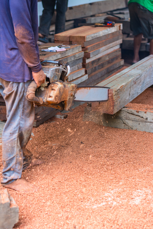 Carpenter is using gasoline engine portable chainsaw cut timber.の写真素材