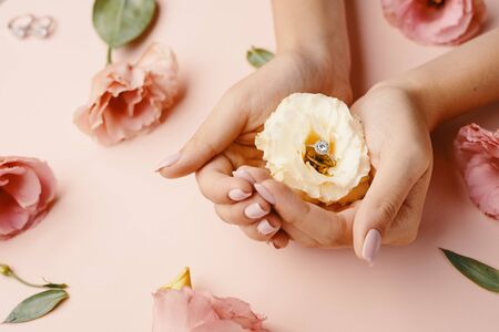 Close-up beautiful sophisticated female hands with yellow flowers on pink background. In flower...