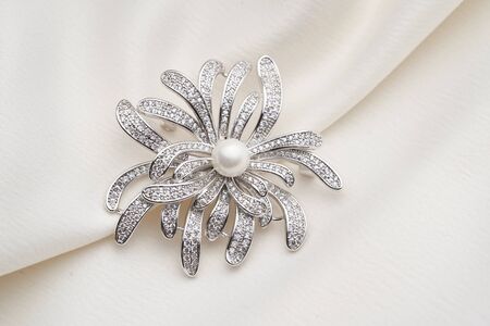 Silver brooch with small diamonds and white pearl,  isolated on white background. Women Accessoriesの写真素材