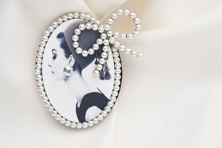Cameo brooch, which is a side portrait of a woman, with small pearls around the edges on a white background. Women accessories.の写真素材