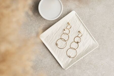 Modern minimalist geometric long stud earrings on white marble plate . Earrings in the form of circles. Women accessories. Closeupの写真素材