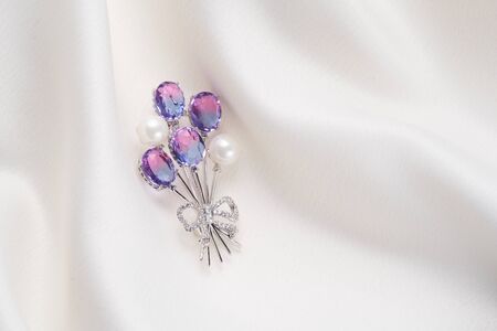 Silver brooch shaped like balloons with small diamonds and pearls, isolated on white background....