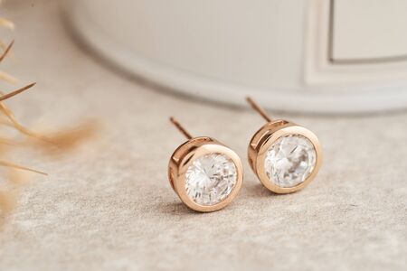 Close up golden stud earrings, with white crystals and diamonds. Beautiful earrings on white background. Women accessoriesの写真素材