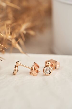 Close up golden stud earrings, with white crystals and diamonds. Beautiful earrings on white background. Women accessoriesの写真素材