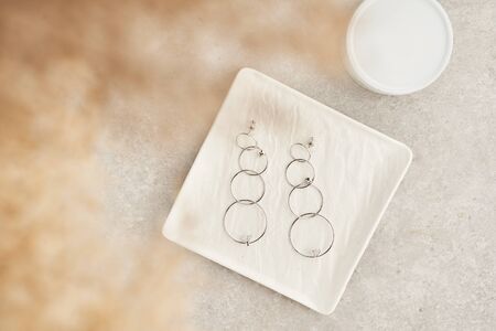 Modern minimalist geometric long stud earrings on white marble plate . Earrings in the form of circles. Women accessories. Closeupの写真素材