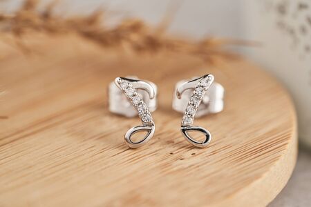 Close up silver stud earrings, with white crystals and diamonds. Beautiful earrings on wooden plate Women accessories, woman's jewelry.の写真素材