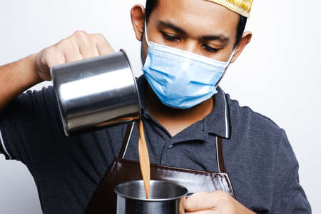 A picture of men preparing teh tarik. Sweet milk tea been pull for mix well and create foam that is...