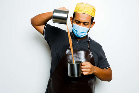 A picture of men preparing teh tarik. Sweet milk tea been pull for mix well and create foam that is...
