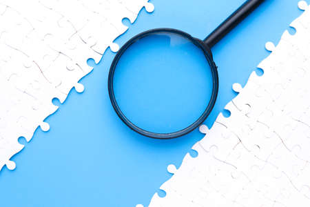 Separated puzzles with magnifying glass on blue background.  For consulting and looking for solution...