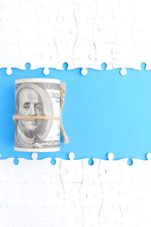 A picture of money with separated jigsaw puzzle with copy space blue background. Financial solution concept.の写真素材