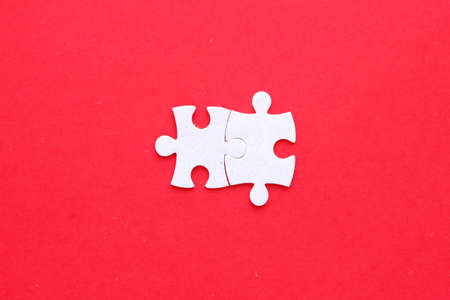 Two pieces of jigsaw puzzle connect on isolated red background.
