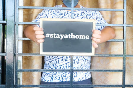 A picture of men wearing N95 face mask, goggle and hood holding blackboard written #stayathome....
