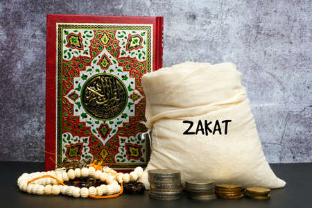 A picture of zakat concept with rice bag, money, Quran and tasbeeh or prayer beads. Large Arabic word mention, the Holy Koran is with variance recitation and rules for the correct pronunciations.の写真素材
