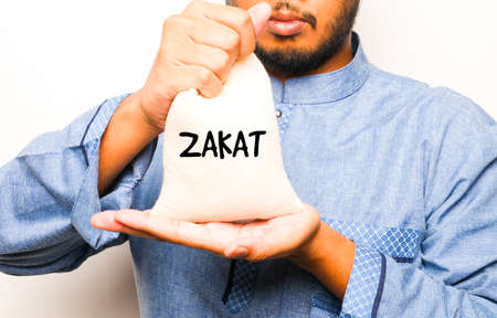 A picture of men holding rice bag with zakat word in sight. Zakat is a form of alms-giving treated in Islam as a religious obligation or tax.の写真素材