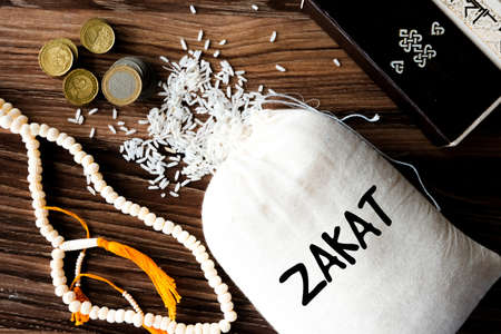 A picture of Zakat rice bag with coins, tasbeeh and part of Quran. Zakat is a form of alms-giving treated in Islam as a religious obligation or tax, importance after solat by Quranic sequence.の写真素材