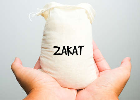 A picture of zakat rice bag with hand perform doa. Zakat is a form of alms-giving treated in Islam...