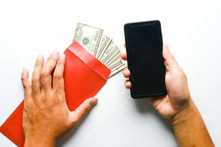 A picture of hand holding envelope with fake money and copyspace smartphone for corruption symbol....