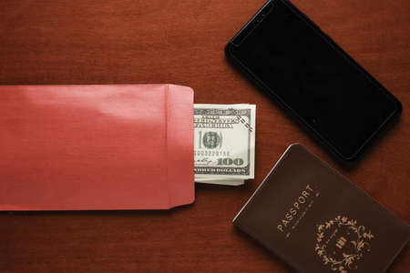 A picture of smartphone, money with envelope and passport on table for International Anti-Corruption...