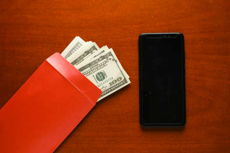 A picture of blank smartphone with envelope filled of fake money on table. International...