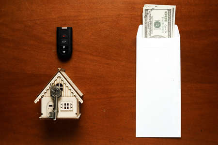 Flatlay picture of envelope contain money, car key, house key and miniature on the table. Variety...