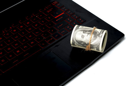 A picture of fake money on laptop on white background. During covid-19 people survive with online business.の写真素材
