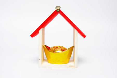 A picture of gold ingot written prosperity in the cart with miniature house white background. During covid-19 Chinese New Year will celebrate in new normalの写真素材
