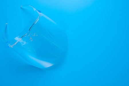 A picture of face shield on blue background. Face shield is needed and advised to wear during...