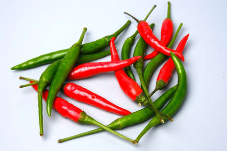 A levitation picture of the hottest green and red small chilli pepper on gray background.
