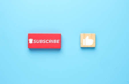 A picture of subscribe on red wooden block and like on wood tiles.の写真素材