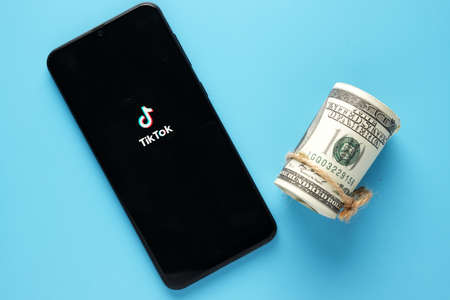 Kuala Lumpur, Malaysia-Circa June, 2021: A picture Tik Tok on smartphone and fake money. Earning with TikTok concept.のeditorial素材