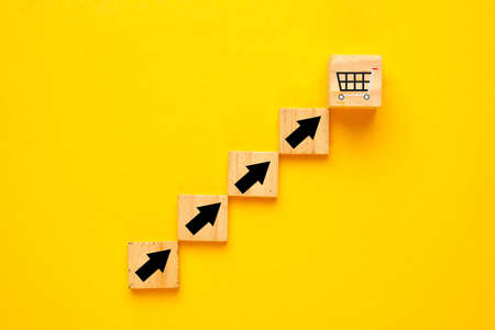 Shopping trolley cart and increase arrow which screen on wooden cube block. Online shopping is growing during  pandemicの写真素材