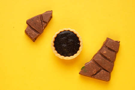 A picture of 4 chocolate tart and bar on yellow background. Food prepared for dessert.の写真素材