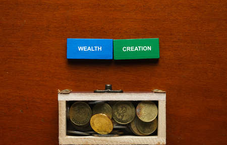 Selective focus of blue and wooden domino written wealth creation with gold chest insight.の写真素材