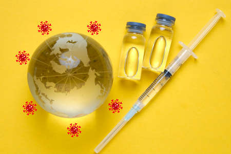 A picture of Covid-19 vaccine and syringe with covid-19 orbitting the globe. Get protected with vaccine from new variant.の写真素材