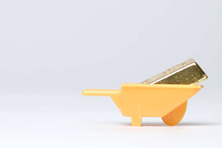 Selective focus part of gold bar miniature with wheelbarrow insight. Wealth creation concept.の写真素材