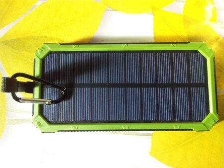 Charger Solar on green background with white USB cord for Charging smartphone phone from the solar battery.の写真素材