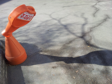 Broken neck cone with shadow on road, Broken NO PARKING cone traffic cone with No-parking sign in Korean lettersの写真素材