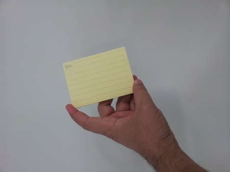 Close-up, selective focus: Hand Holding Yellow sticky Note Paper against white background with copy space for textの写真素材