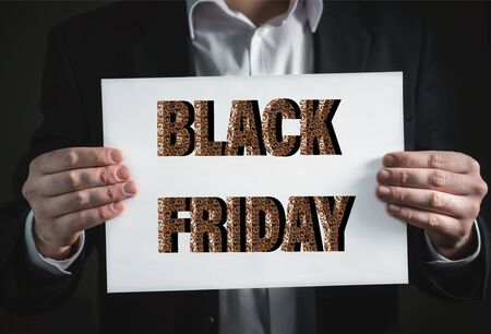 Man hands holding white cardboard or placard against black background with words of black fridayの写真素材