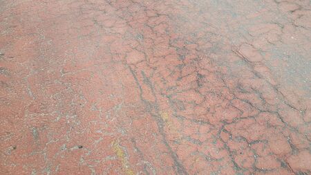 Red colored damaged road or paved pathway with crackes of different shpaes. Cracked texture with copy space for text and messagesの写真素材