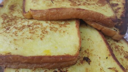 Closeup view of freshly prepared half fried slices of toast bread. Food background for bakery items.