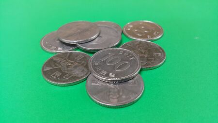 Silver shining Korean won coin scattered over a green floor.