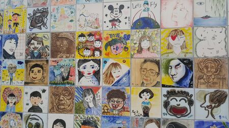 Chuncheon city hall, South Korea-March-25, 2019: Paintings and sculpted faces of people on the concrete wall for memoir in a public park.のeditorial素材